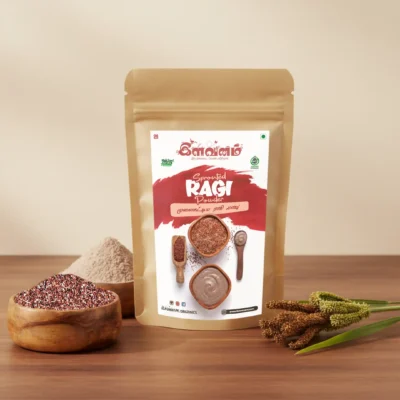 Ilavanam Organics Sprouted Ragi Powder pouch surrounded by wooden bowls of ragi seeds, ground powder, and fresh ragi stalks.